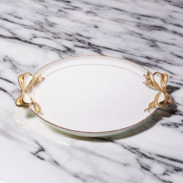 A white tray with gold accents and ribbon handles on a marble surface.