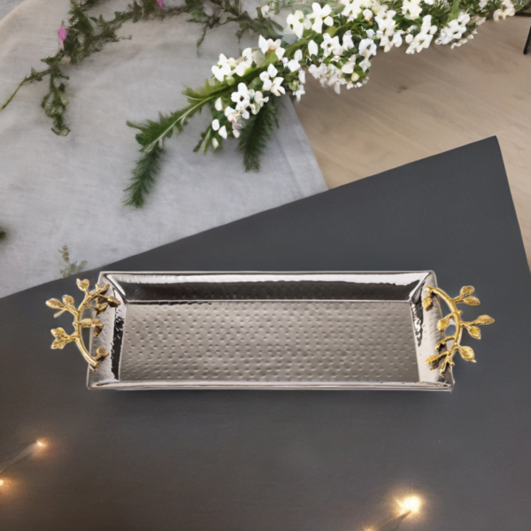 Stainless steel rectangle serving tray with hammered styling and gold accented handles on a black top.