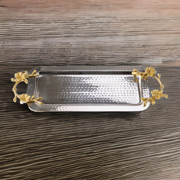 Rectangle hammered stainless steel serving tray adorned with gold handles on a wood table.
