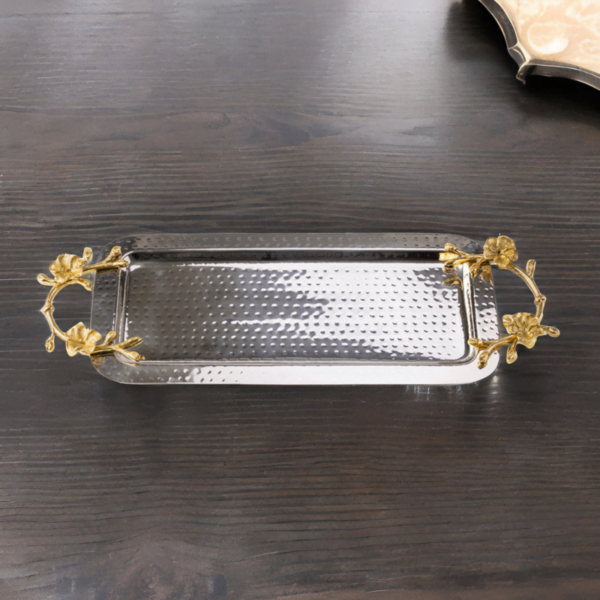 Rectangle hammered stainless steel serving tray adorned with gold handles on a dark wood table.