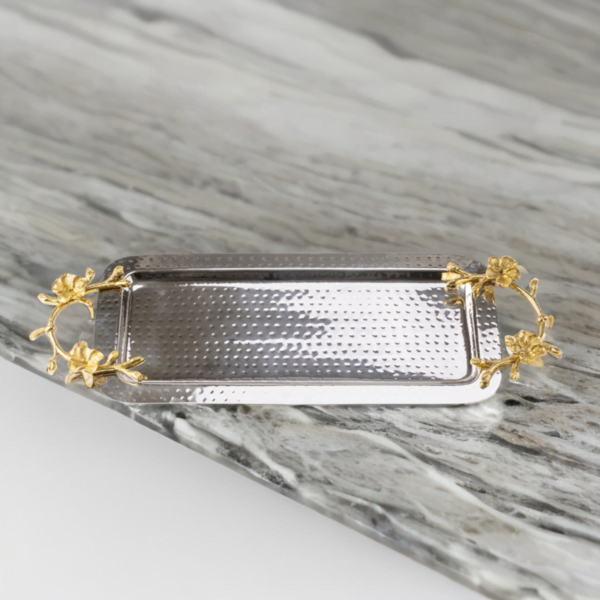 Rectangle hammered stainless steel serving tray adorned with gold handles on a marble surface.
