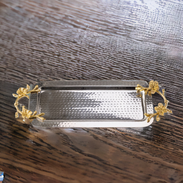 Rectangle hammered stainless steel serving tray adorned with gold handles on a wooden table.