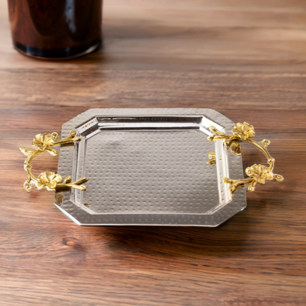 An Octagon Silver Tray with gold handles on a table.