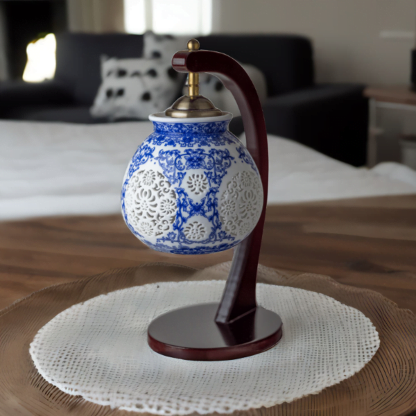 A wood lamp with a porcelain shade adorned with oriental blue and white flower styling.