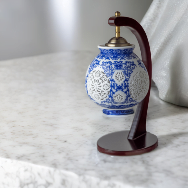 A wood lamp with a porcelain shade adorned with oriental blue and white flower styling on a marble table.