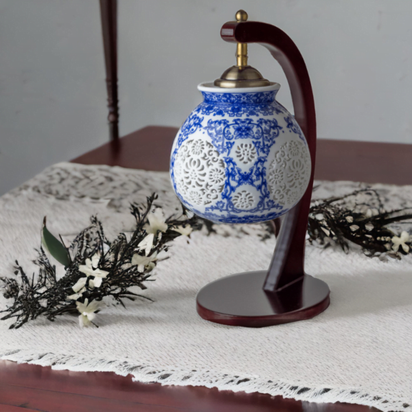 A wood lamp with a porcelain shade adorned with oriental blue and white flower styling.
