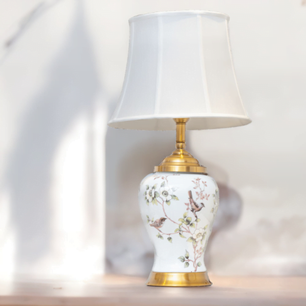 A white porcelain lamp and white shade, gold accents and painted flowers and birds.