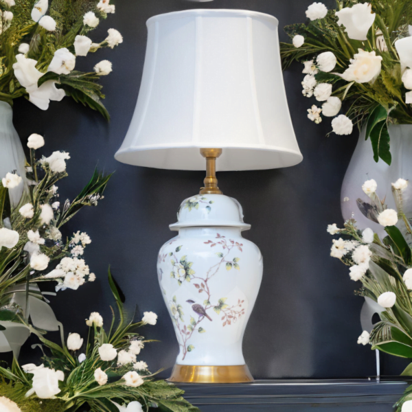 A white ceramic lamp with matching white shade, adorned with flowers and bird design, and gold accents.