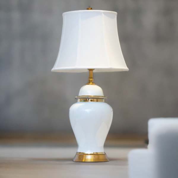 A white lamp with gold accents and matching white shade.
