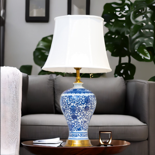 A blue and white lamp adorned with gold accents and stylish blue and white flower patterns on a table in a living room.