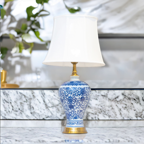 A blue and white lamp adorned with gold accents and stylish blue and white flower patterns sitting on a marble counter.