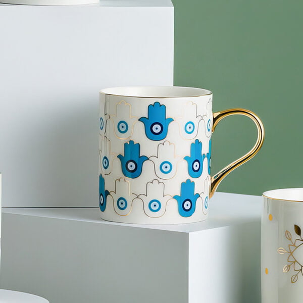 mug with gold edges and hamsa blue and white prints on a white mug