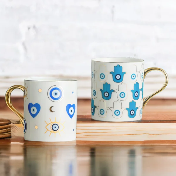 Azure Hamsa and Azure Evil Eye Mugs on wooden top.