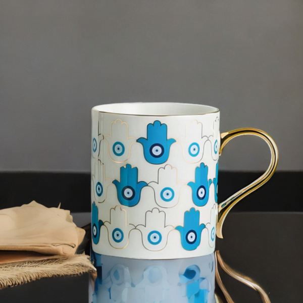 An Azure Hamsa Hand Mug, Blue and White with Gold accents.
