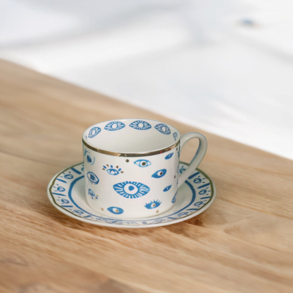 An Evil Eye Blessing Set cup and saucer on a wooden table.