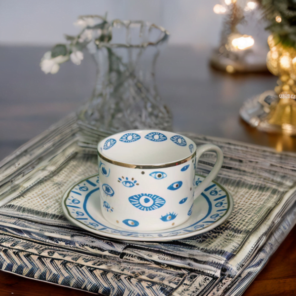 An Evil Eye Blessing Set cup and saucer on a table.