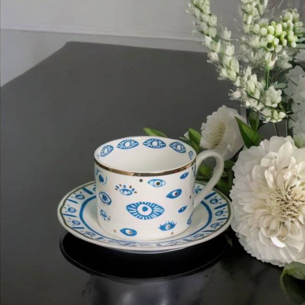 An Evil Eye Blessing Set tea cup and saucer in blue and white on a table.