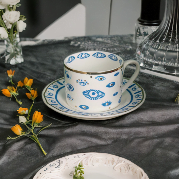 An Evil Eye Blessing Set tea cup and saucer on a table.