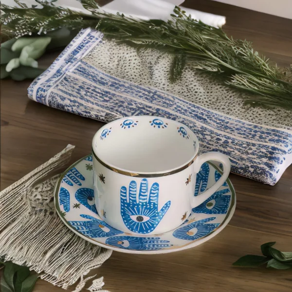 A Hamsa Blessings Set cup and saucer on a table.