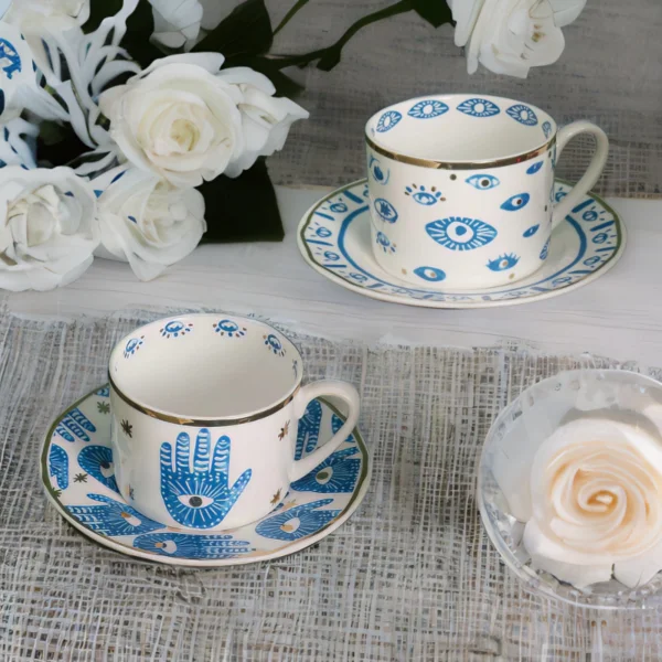 An evil eye and hamsa hand coffee cups with matching saucers.