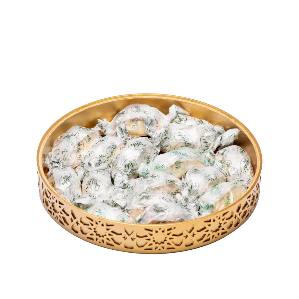 A vibrant gold decorative tray with an intricate and colourful design filled with sweets.