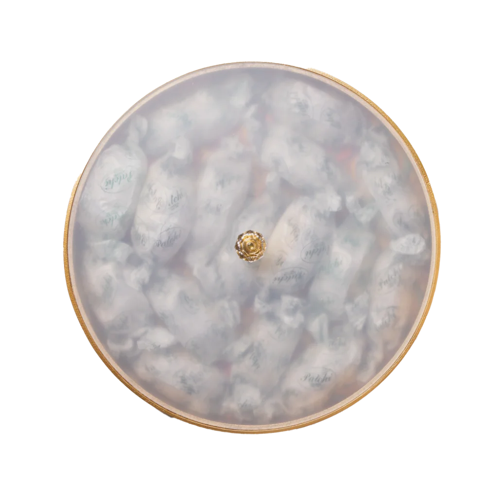 A vibrant gold decorative tray with an intricate and colourful design filled with arabic sweets.