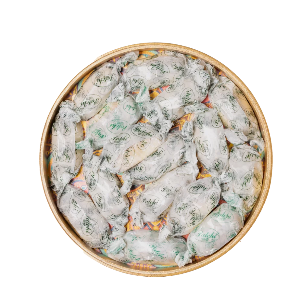 A vibrant gold decorative tray with an intricate and colourful design filled with ramadan sweets.