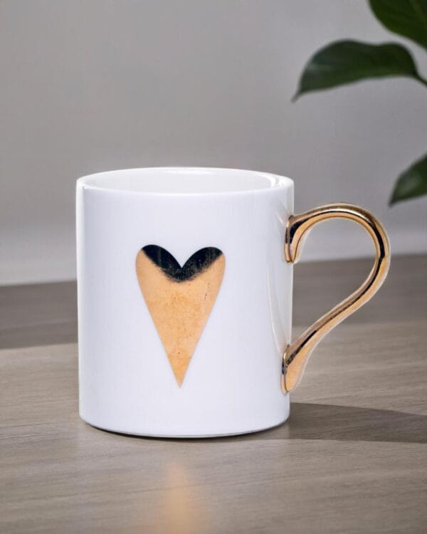 White ceramic mug adorned with a gold handle and a single golden heart