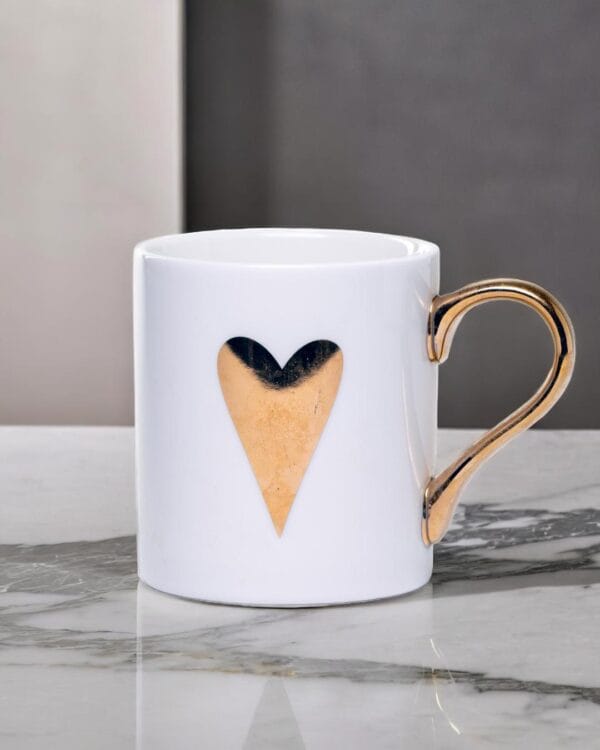 White ceramic mug adorned with a gold handle and a single golden heart