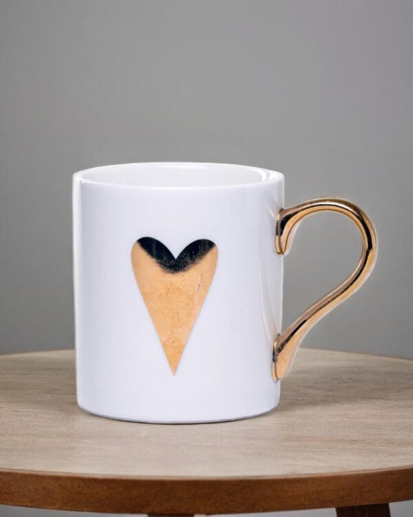 White ceramic mug adorned with a gold handle and a single golden heart