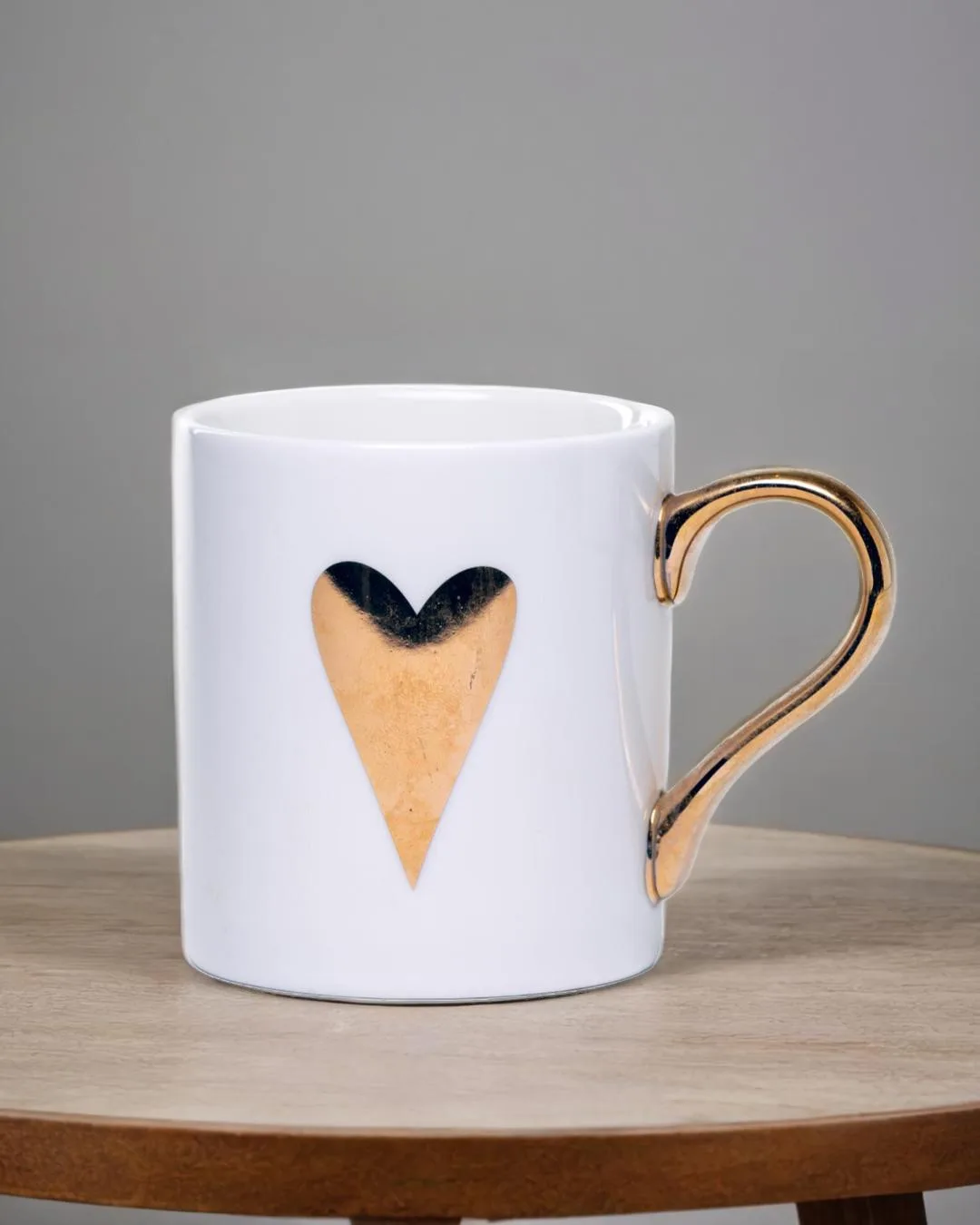 White ceramic mug adorned with a gold handle and a single golden heart