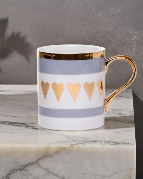 Ceramic mug adorned with golden hearts and a golden handle on a marble counter