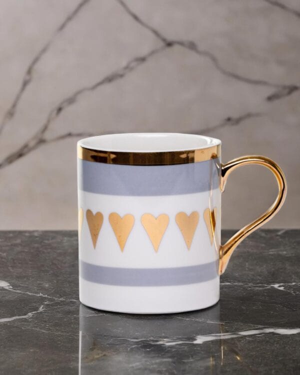 Ceramic mug adorned with golden hearts and a golden handle.