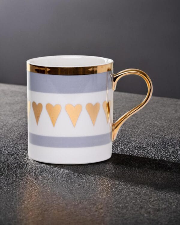 Ceramic mug adorned with golden hearts and a golden handle.