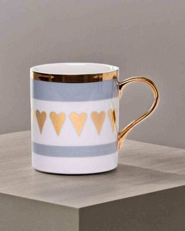 Ceramic mug adorned with golden hearts and a golden handle.