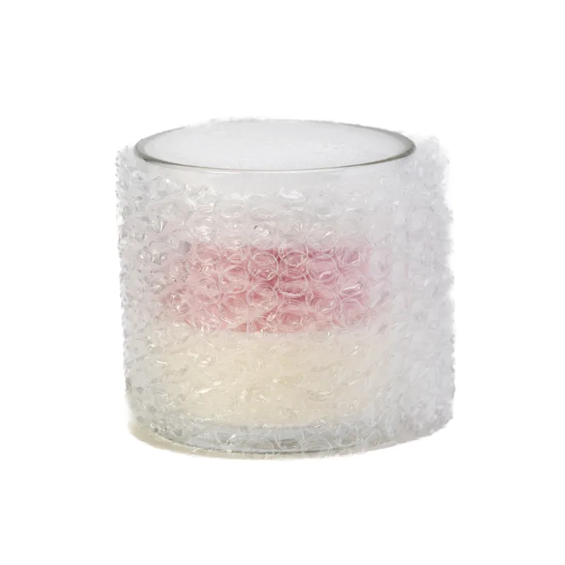A rose candle in a glass jar wrapped in transparent shipping bubble wrap.