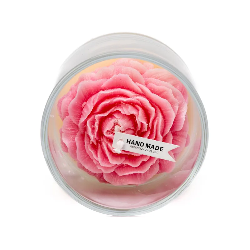 A rose candle in a glass jar features a pink and white flower-shaped wax design.