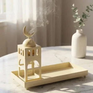 Cream metal minaret-shaped incense burner with crescent moon topper releasing fragrant smoke, paired with matching rectangular tray